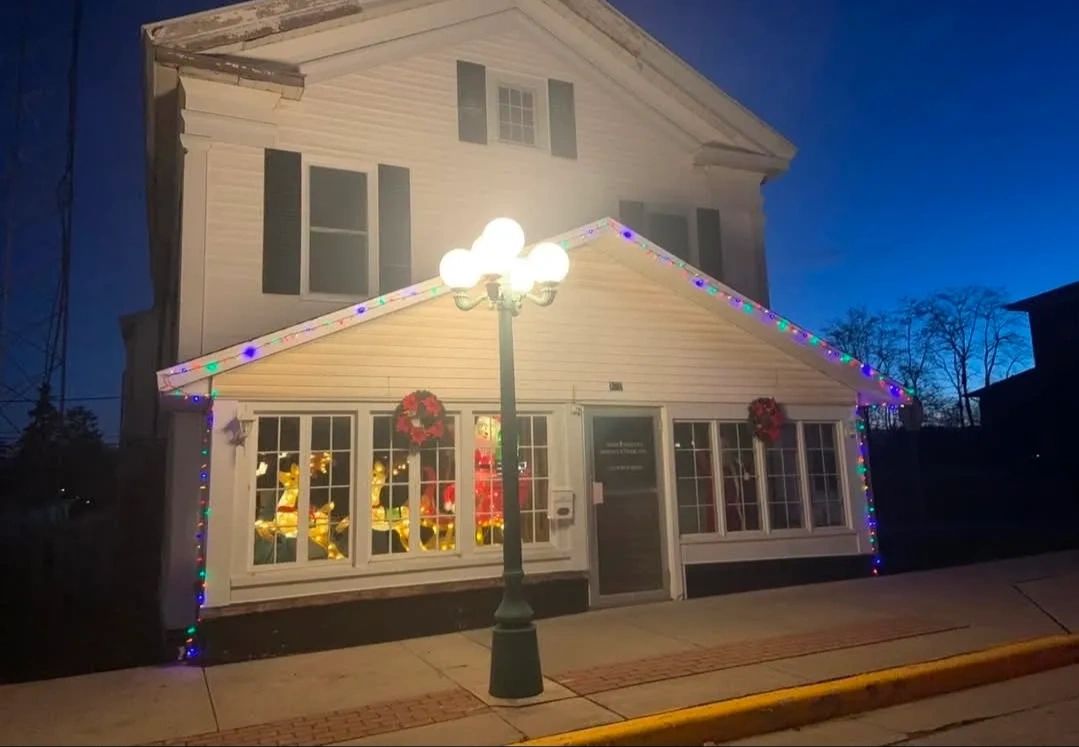 The Miracle Tree building on West Main Street in Albion, lit up for Christmas at dusk