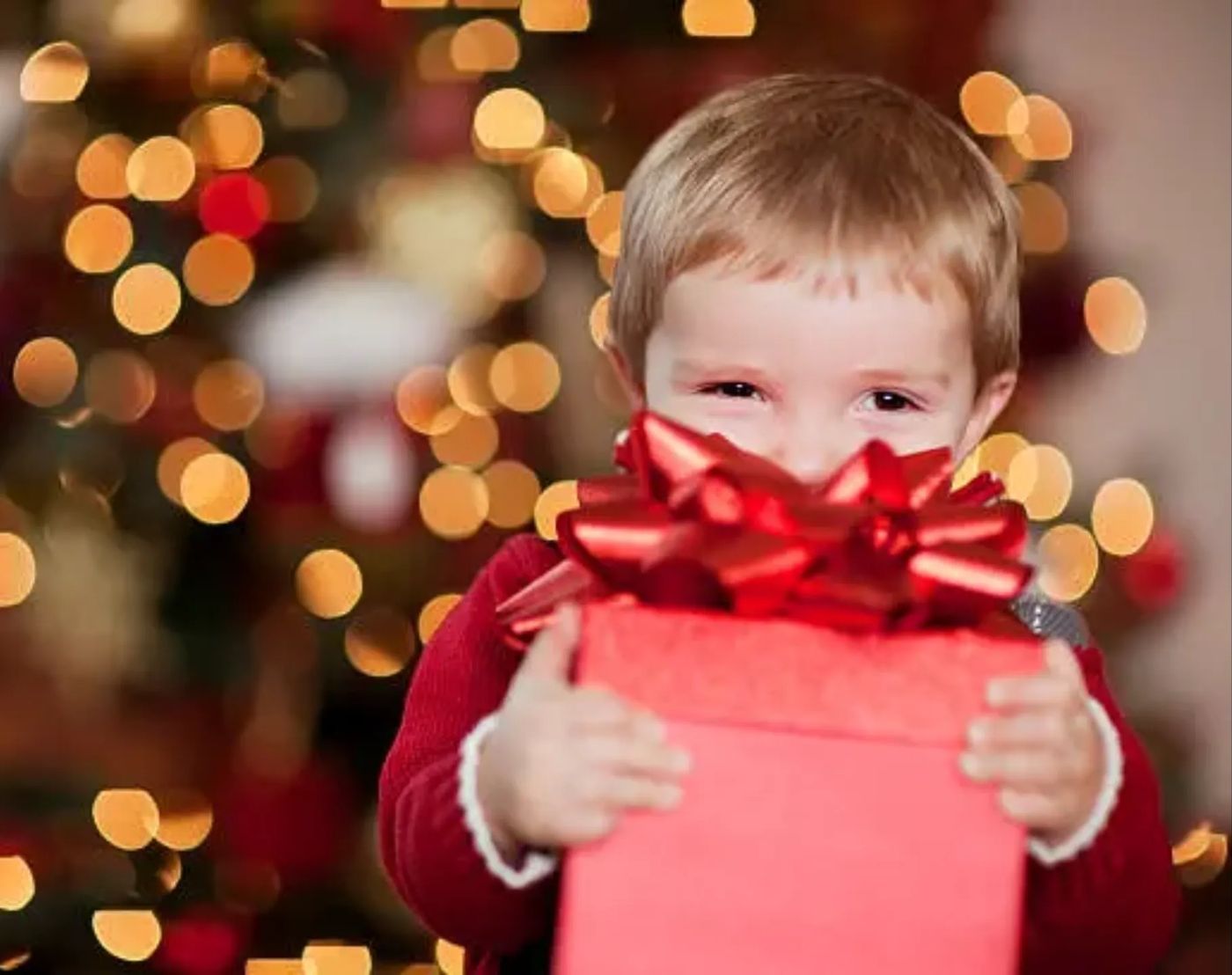 A smiling little boy holding a wrapped Christmas present