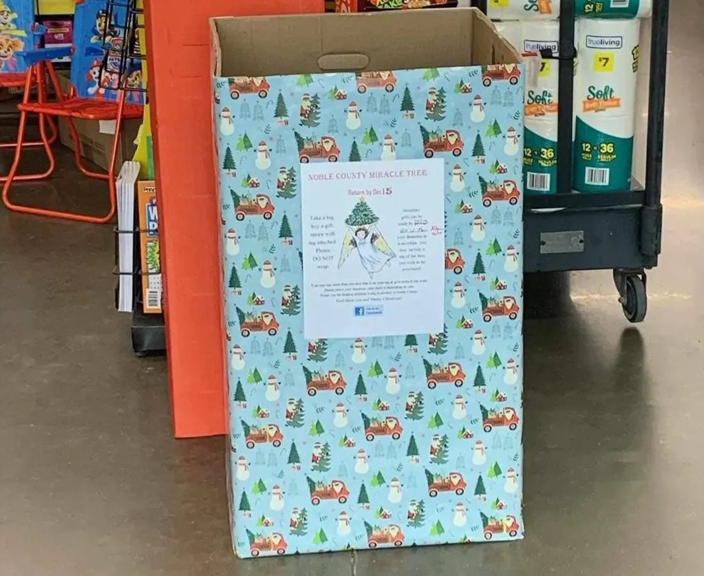 A Miracle Tree donation box wrapped in snowman paper inside a store