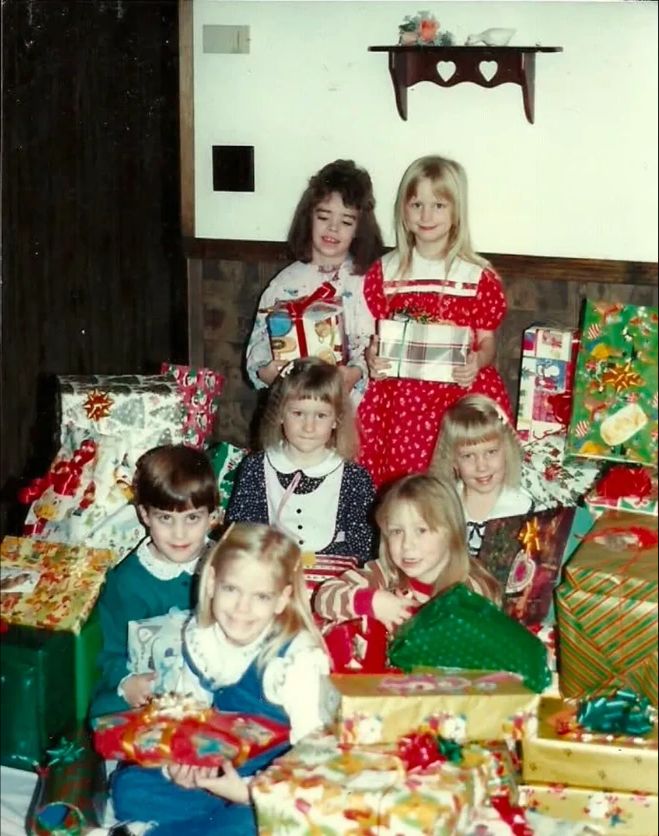 A group of young Girl Scouts surrounded by wrapped Christmas presents